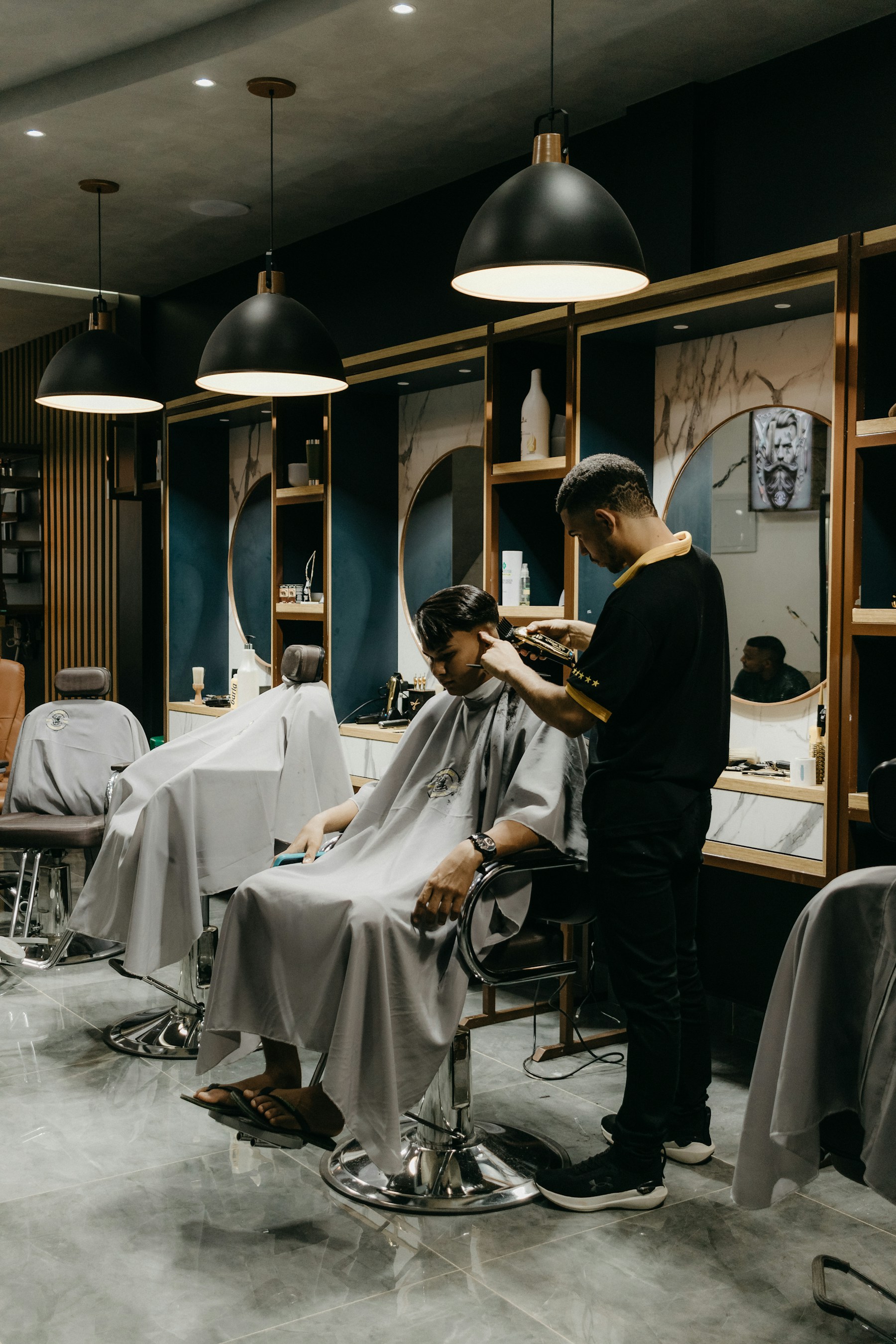 A barber carefully shaping a haircut in a warmly lit shop