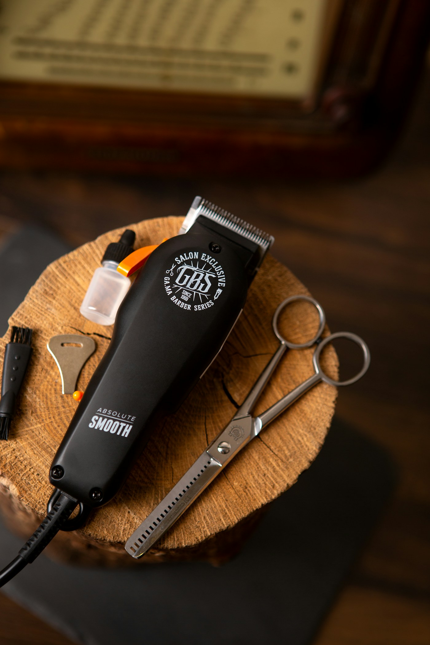 Professional clippers and scissors arranged on a wooden stool